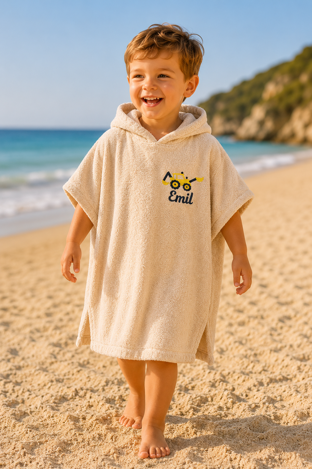 Junge trägt Badeponcho, der mit einem gelben Radlader und Name bestickt ist