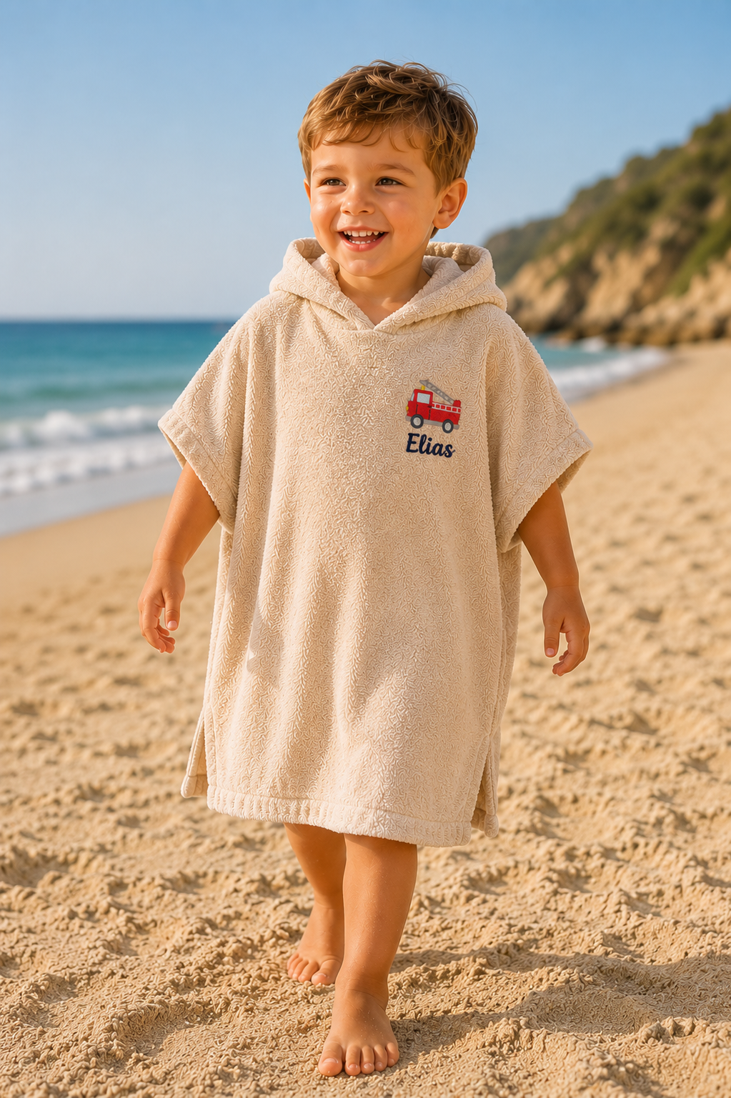 Junge am Strand mit personalisiertem Badeponch mit Feuerwehr Motiv