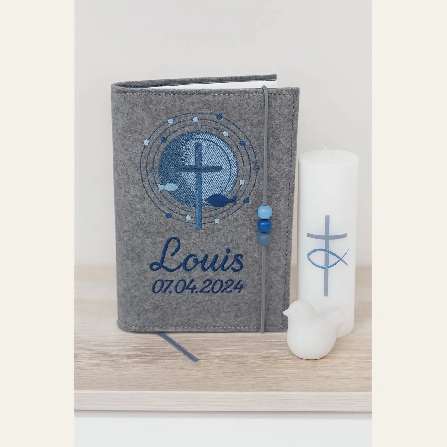 Gotteslobhülle Kreuz mit Schrein in mittelgrauen Filz bestickt mit Name und Datum der Erstkommunion, mit Kommunionkerze dekoriert