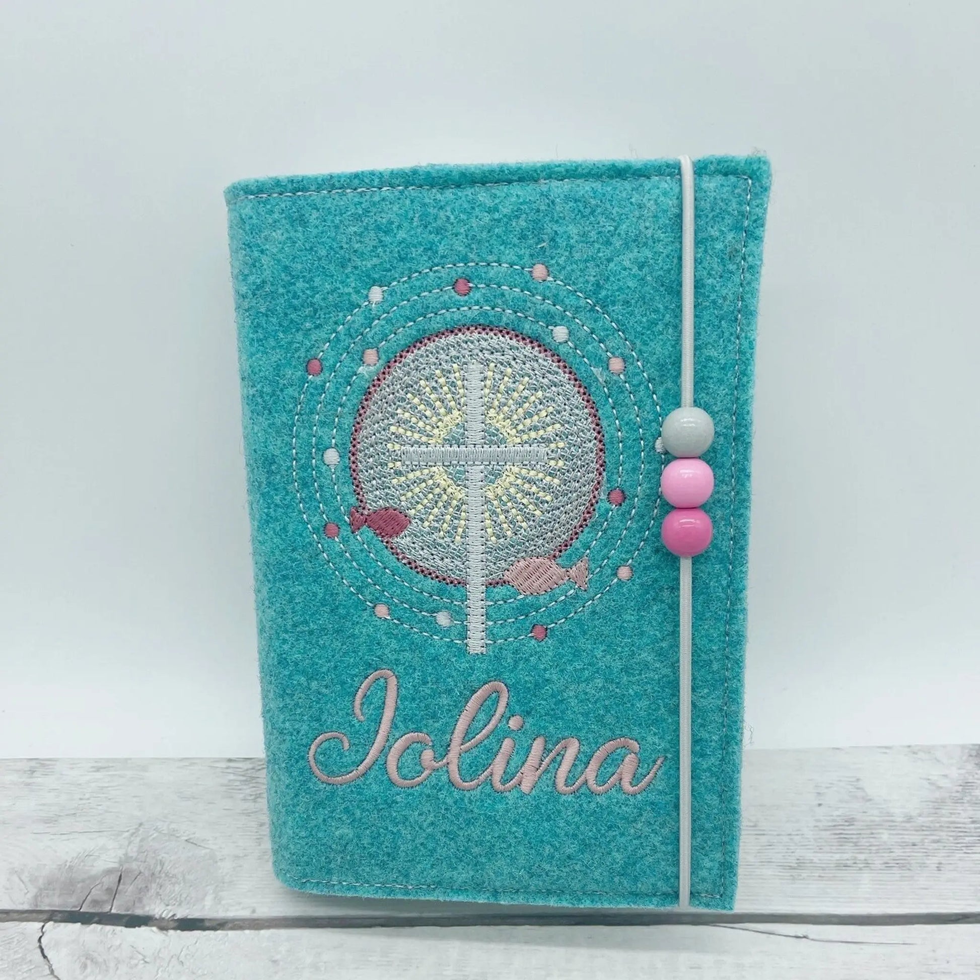 Gotteslobhülle Kreuz mit Schrein bestickt aus türkisem Stickfilz, Stickfarbe altrosa, mit Gummi + Perlen