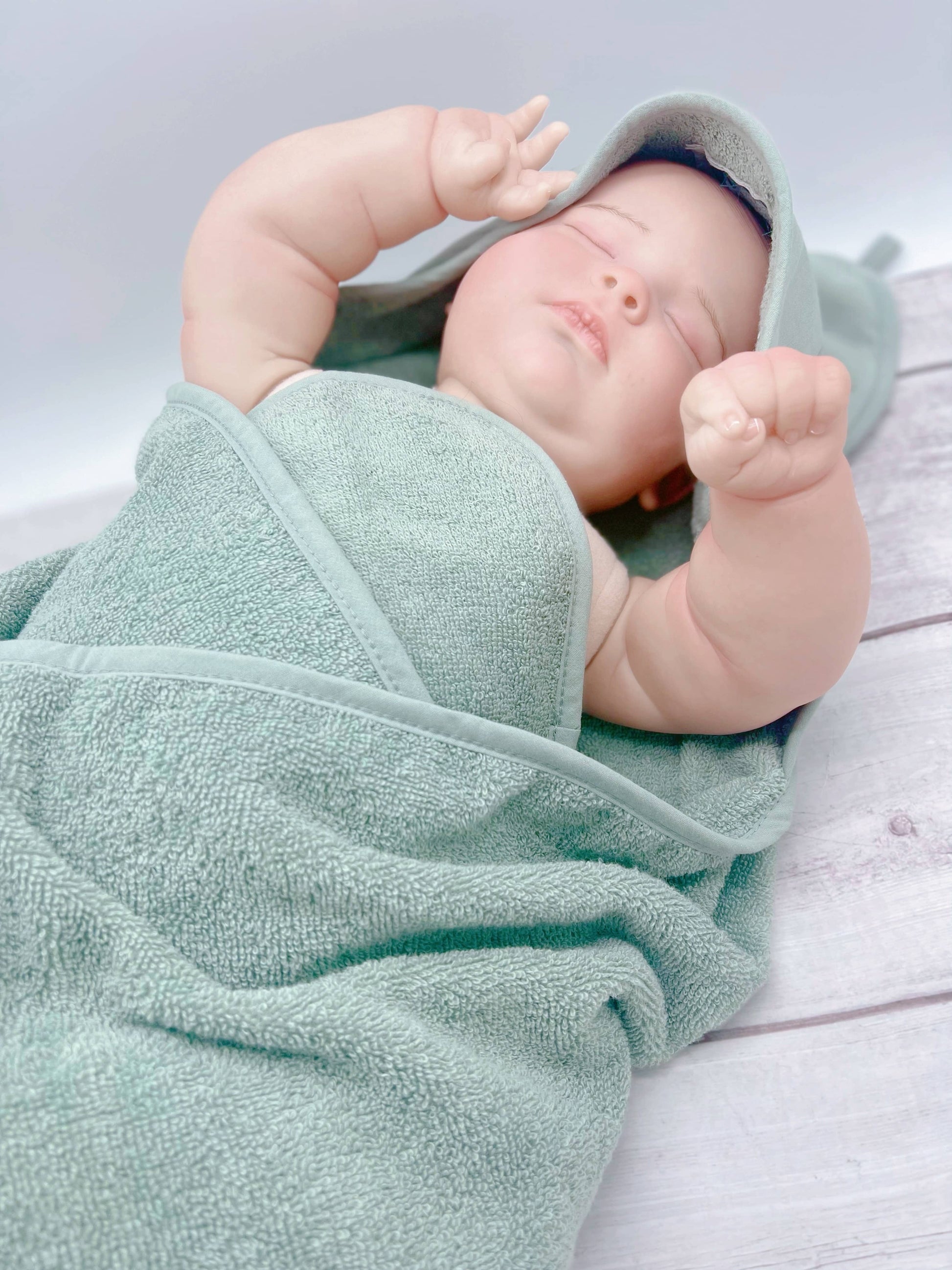 Babypuppe eingewickelt in Kapuzenbadetuch