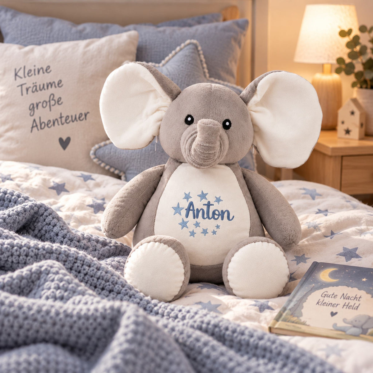 Kuscheltier Elefant mit Namen Anton und Sternen im gemütlichen Kinderbett mit blauer Dekoration