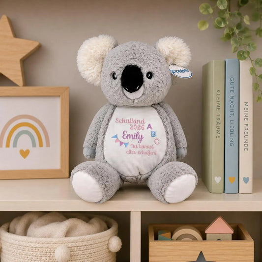 Kuscheltier Koala mit Namen bestickt im Regal zwischen Kinderbüchern