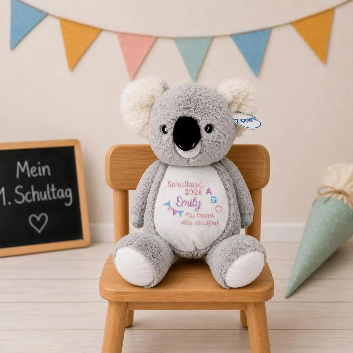 Kuscheltier Koala mit Namen bestickt auf einem Kinderstuhl mit Schultüte und Wimpelkette